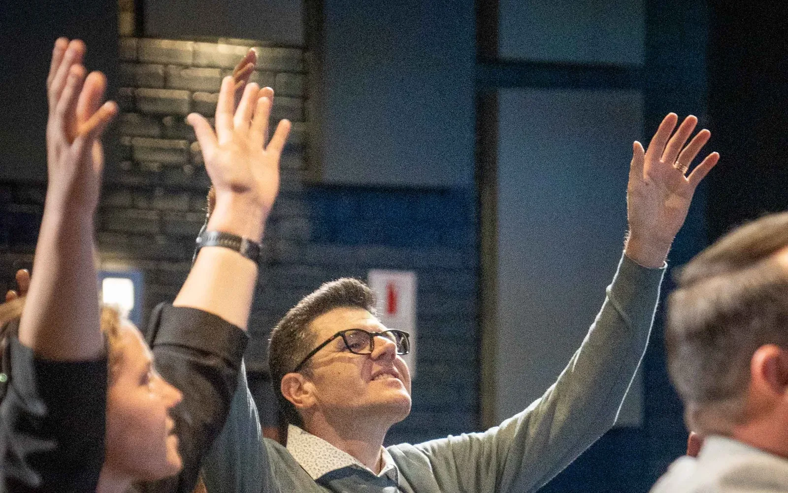 Hands raised in worship across the room