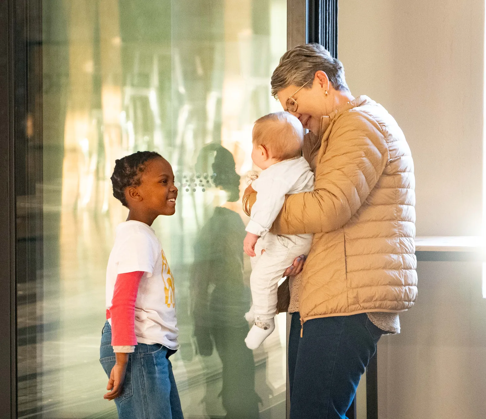 Held close across generations — a baby and a child in the family's care